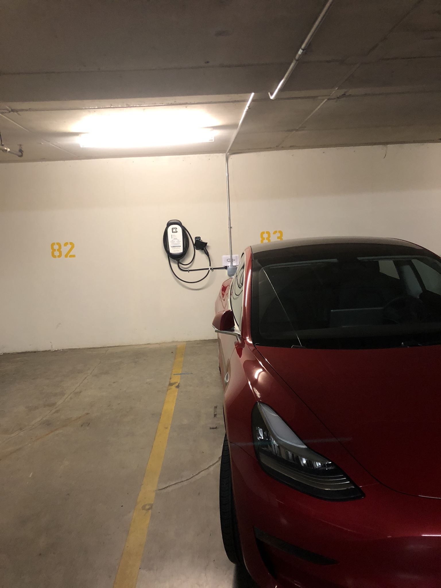 Tesla Wall Mounted EV Charging Station with red Tesla connected to it