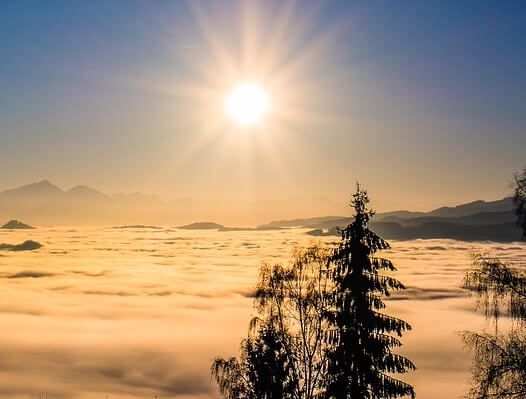 Shining sun above the clouds and treetops